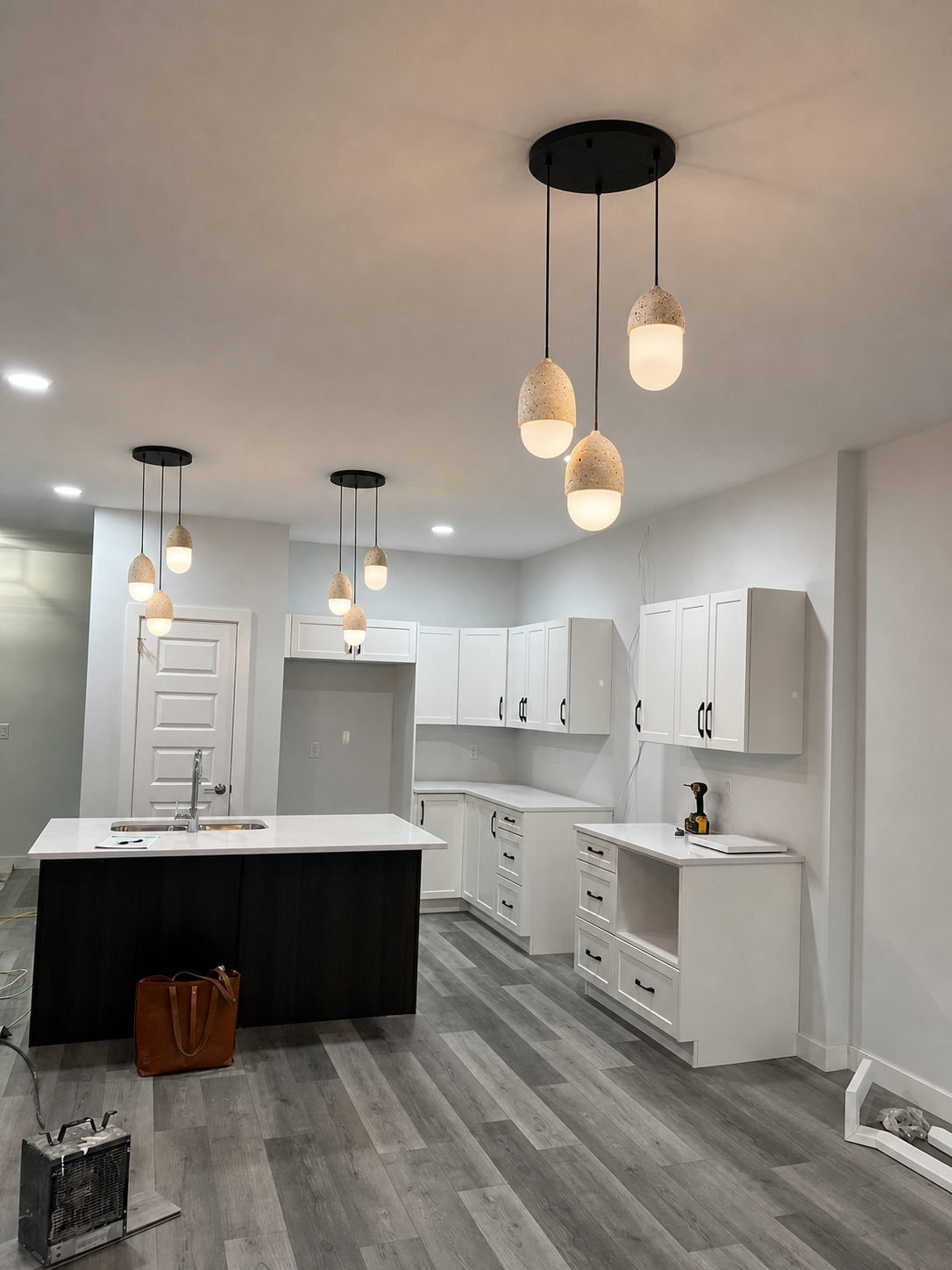 Multiple three-light travertine pendants installed across a customer kitchen