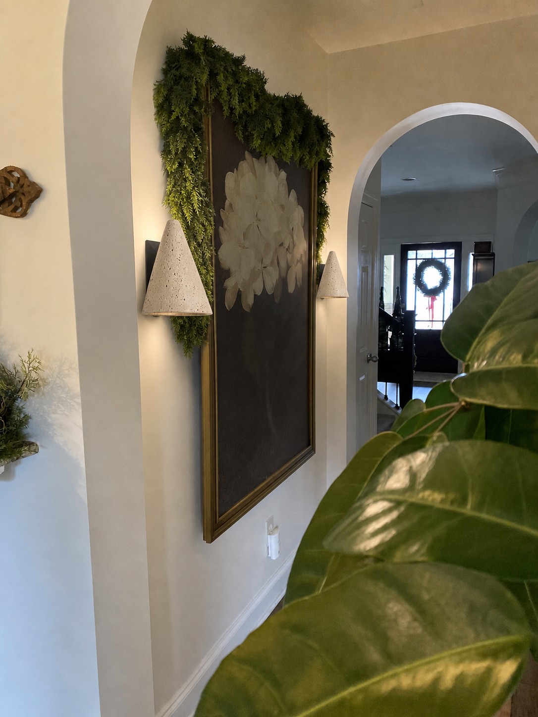 Pair of travertine cone wall sconces installed beside artwork in a customer hallway
