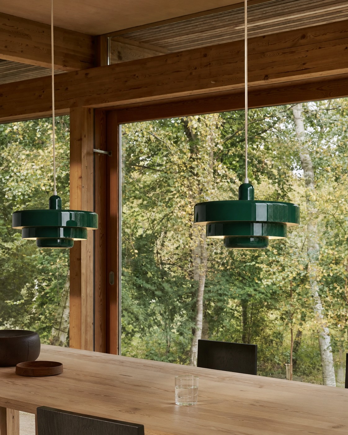 Two green layered pendant lights above a timber dining table