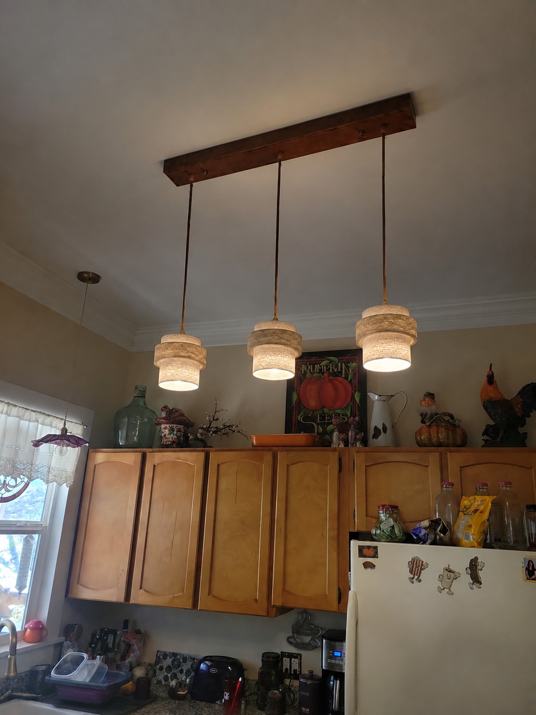 Three-head travertine pendant switched on above a customer kitchen work area