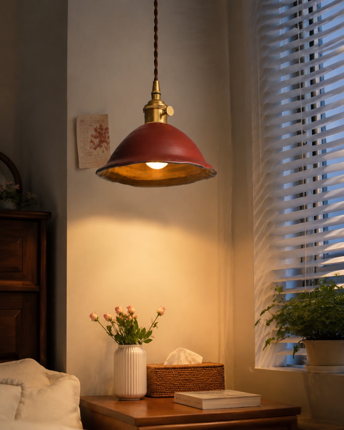 Red glazed ceramic pendant beside a bed