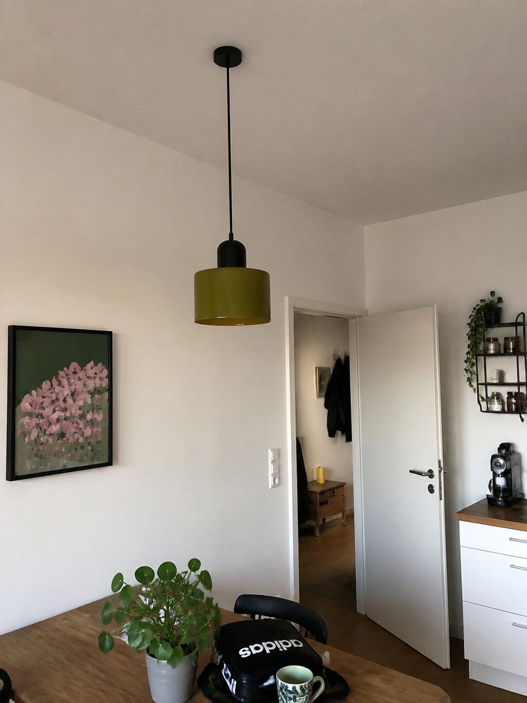 Colgante cilíndrico verde oliva en una cocina luminosa