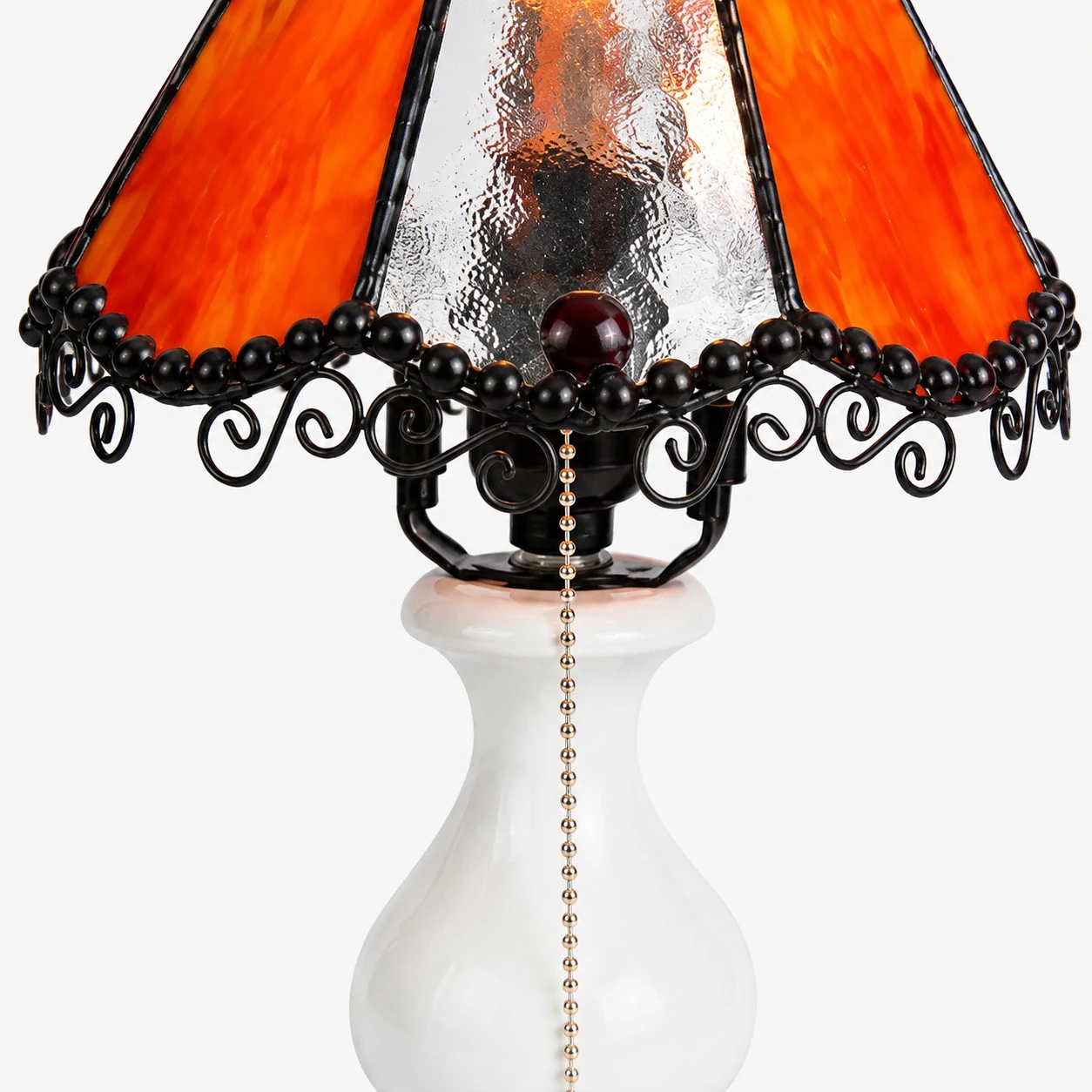 Close view of amber stained glass shade, black lace trim and decorative lamp frame