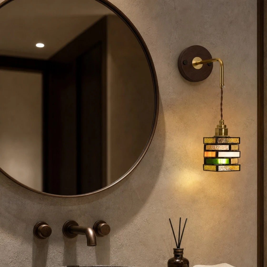 Colorful glass wall sconce beside a round mirror