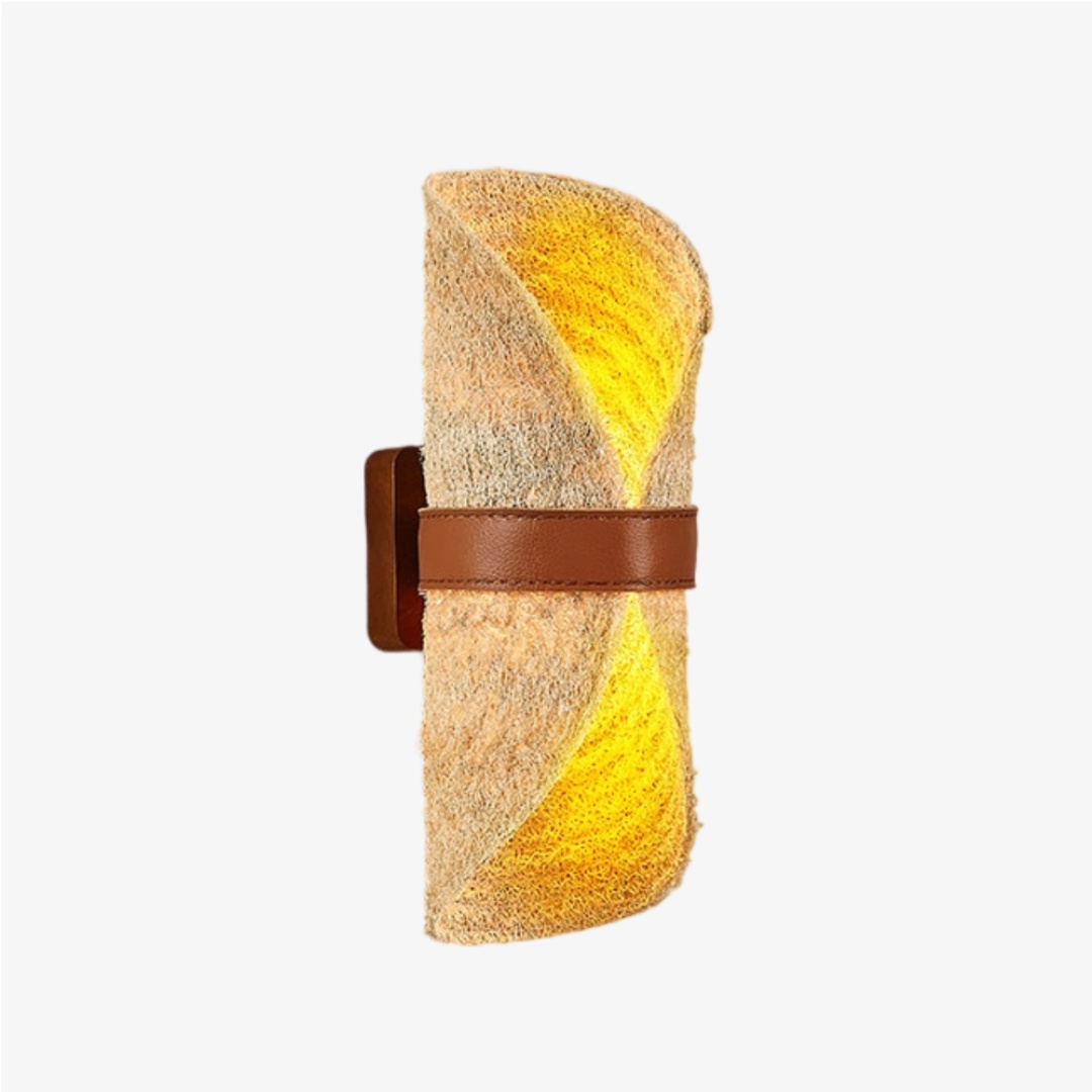 Beige natural loofah wall sconce with a brown leather band illuminated