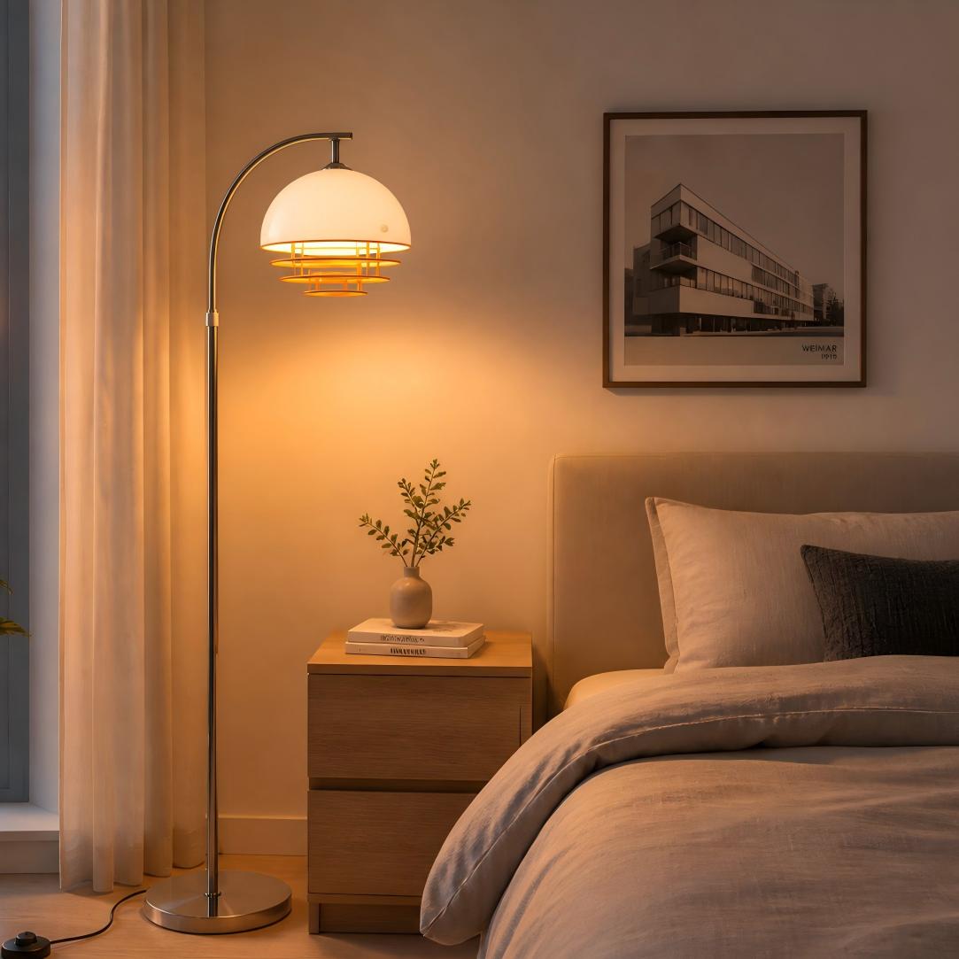 Afterglow curved floor lamp with warm white-orange glass shade in a bedroom