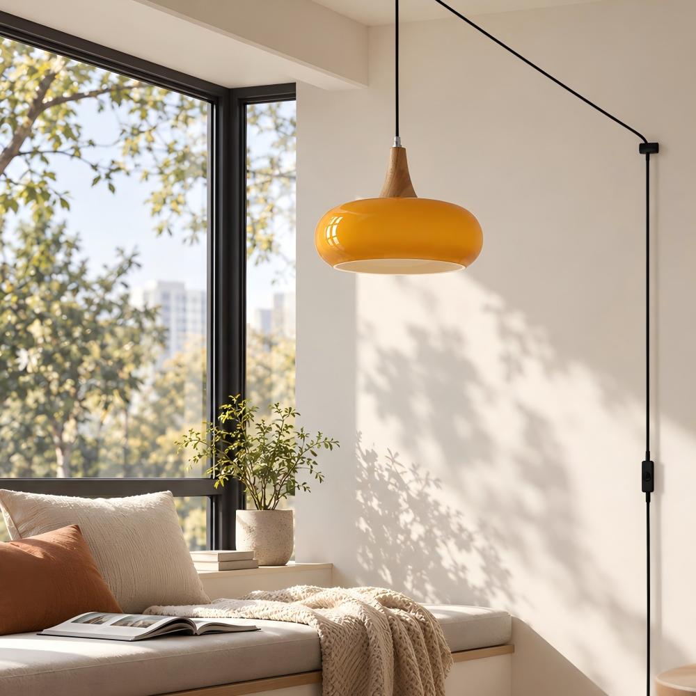 Orange hänglampa i glas med stickkontakt vid ett fönsterhörn